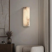 Applique murale design en marbre et laiton, format vertical, diffusant une lumière douce et homogène, idéale pour une salle de bain moderne ou un intérieur contemporain