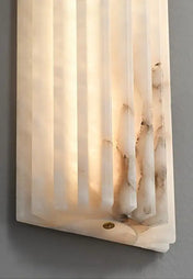 Applique murale design en marbre et laiton, format vertical, diffusant une lumière douce et homogène, idéale pour une salle de bain moderne ou un intérieur contemporain